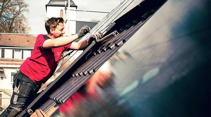 Person hält Schraubenschlüssel und arbeitet an einer großen Metallmaschine, Nahaufnahme der Hände und des Werkzeugs, industrielle Umgebung sichtbar.