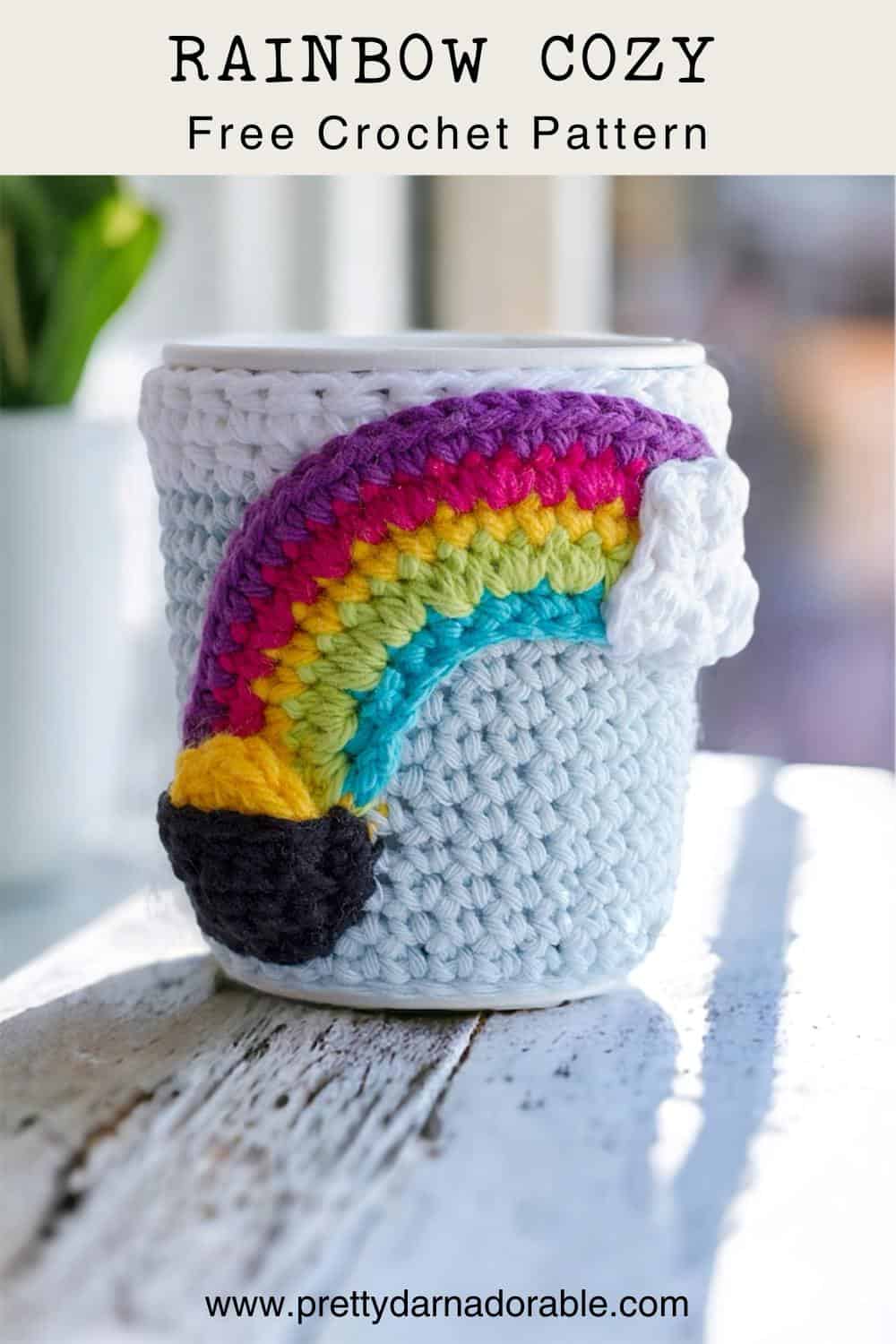Crochet cup cozy with rainbow with cloud on one side and pot of gold on the other