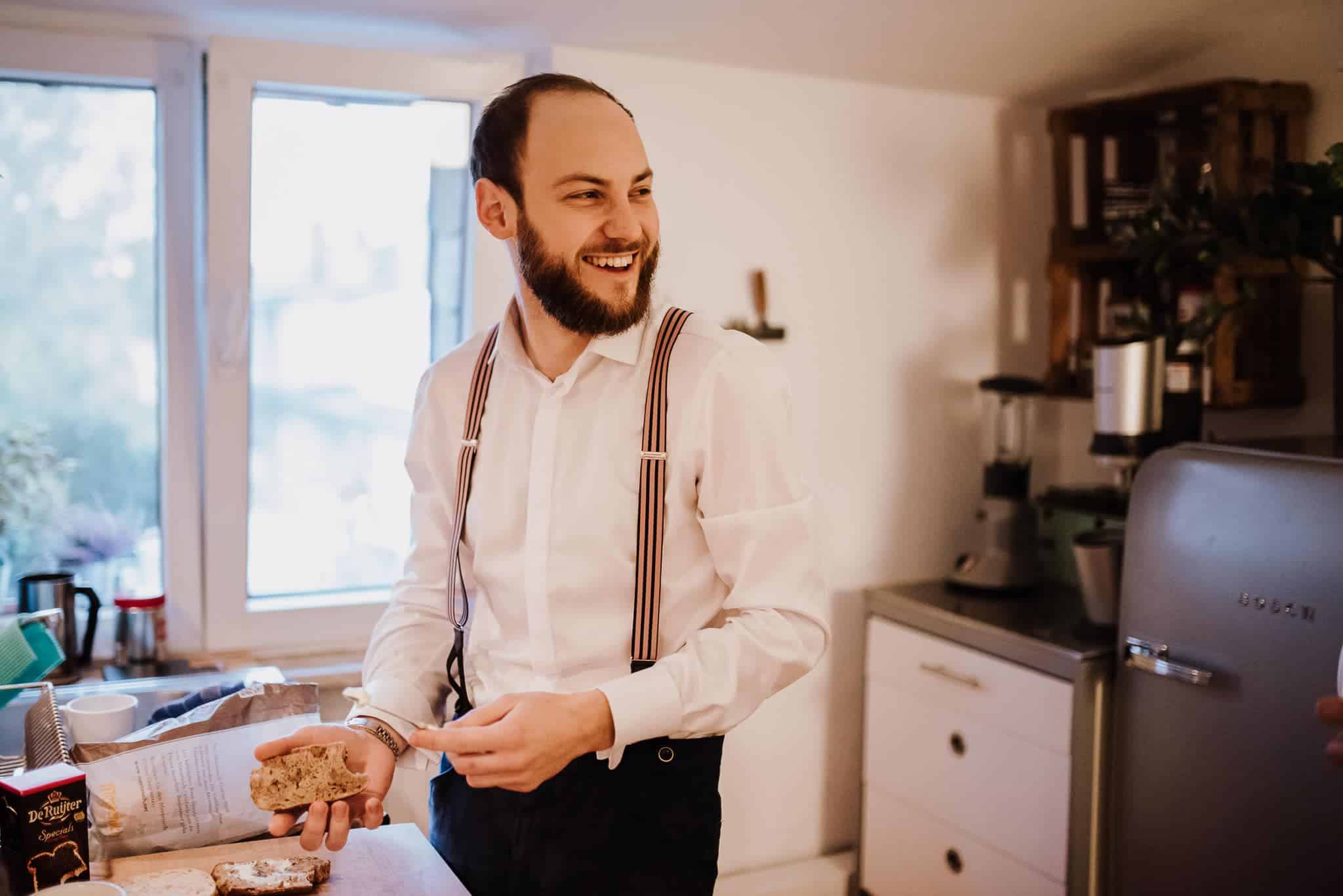 Ein Bräutigam lacht am Morgen der Hochzeit beim Frühstück – Hochzeitsreportage NRW.