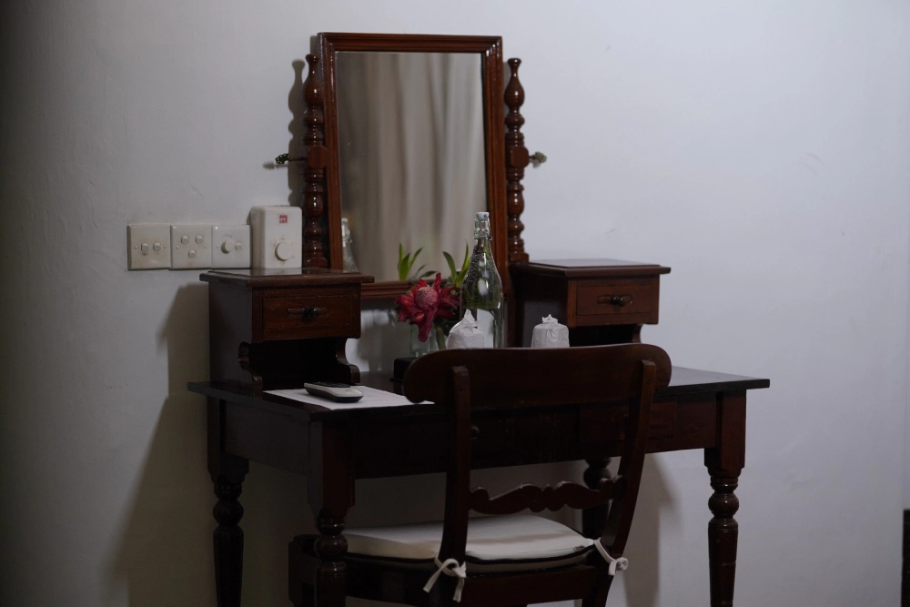 A small table with a chair and a mirror in the Connelian room of Adigar's manor.