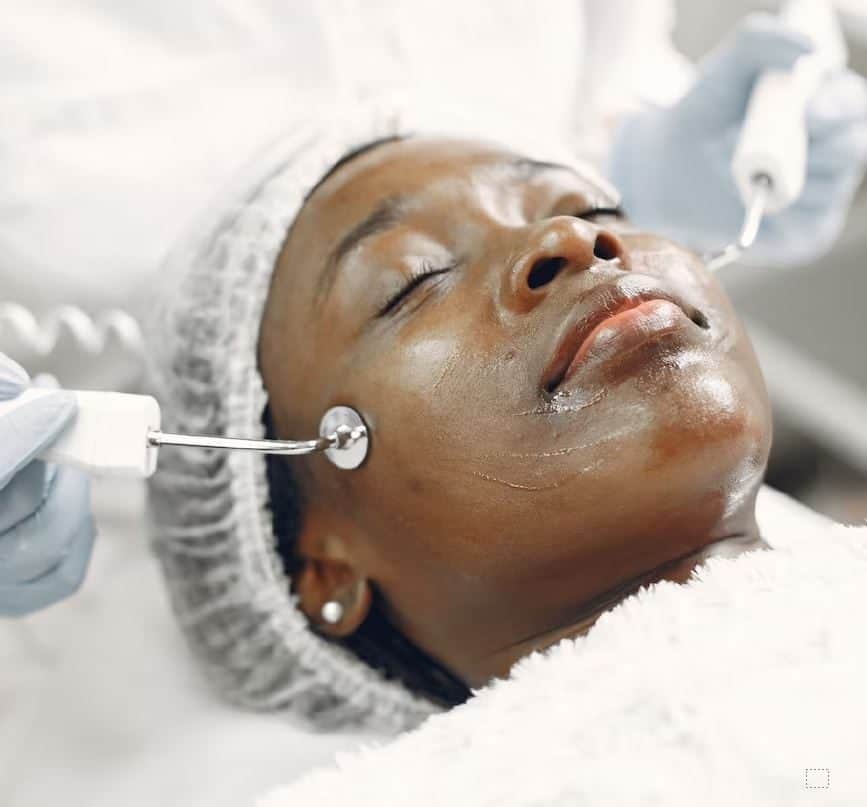 Woman receiving facial treatment with skincare device