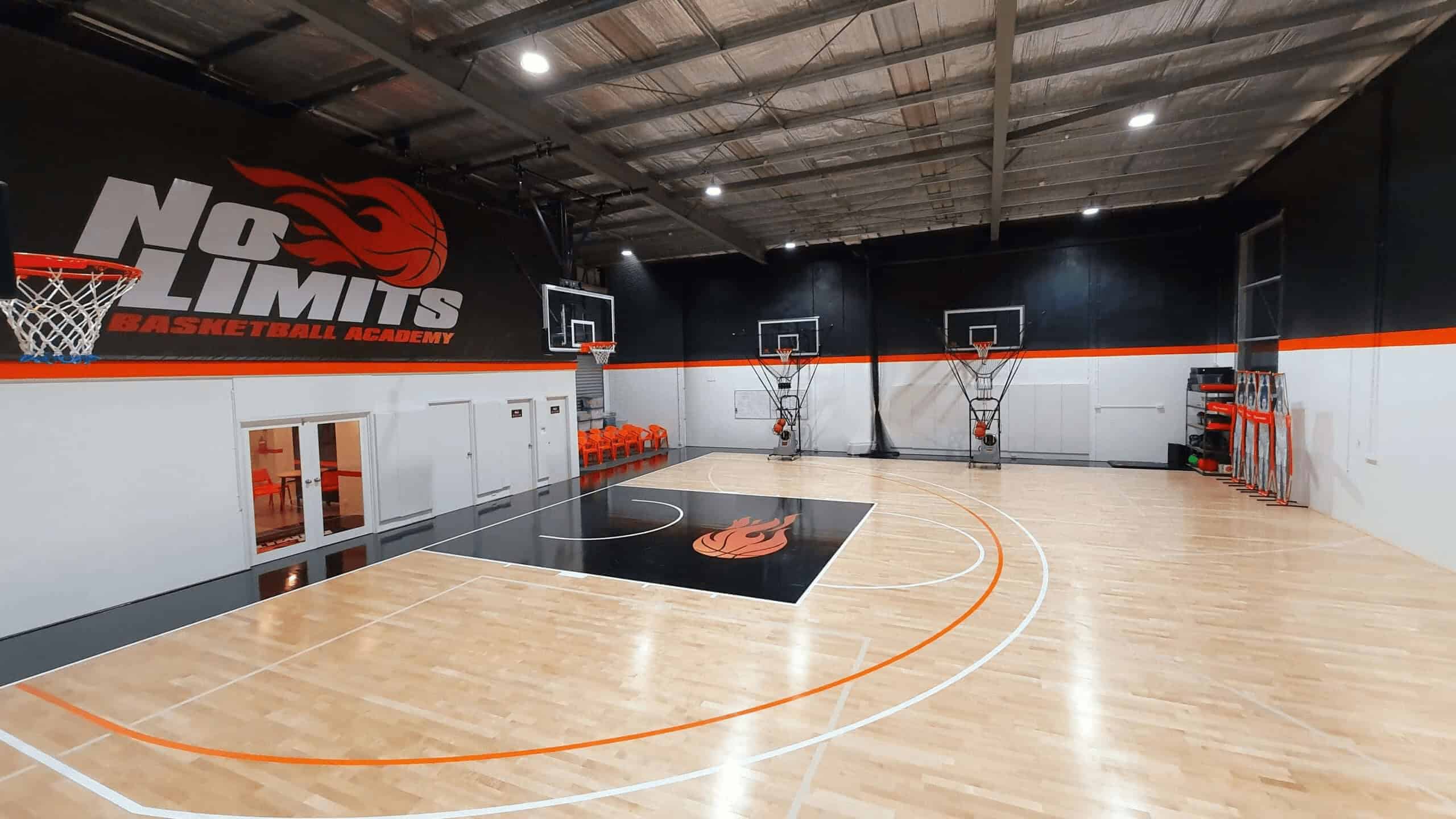 Bright indoor basketball court at No Limits Basketball Academy, equipped with multiple hoops and training gear.