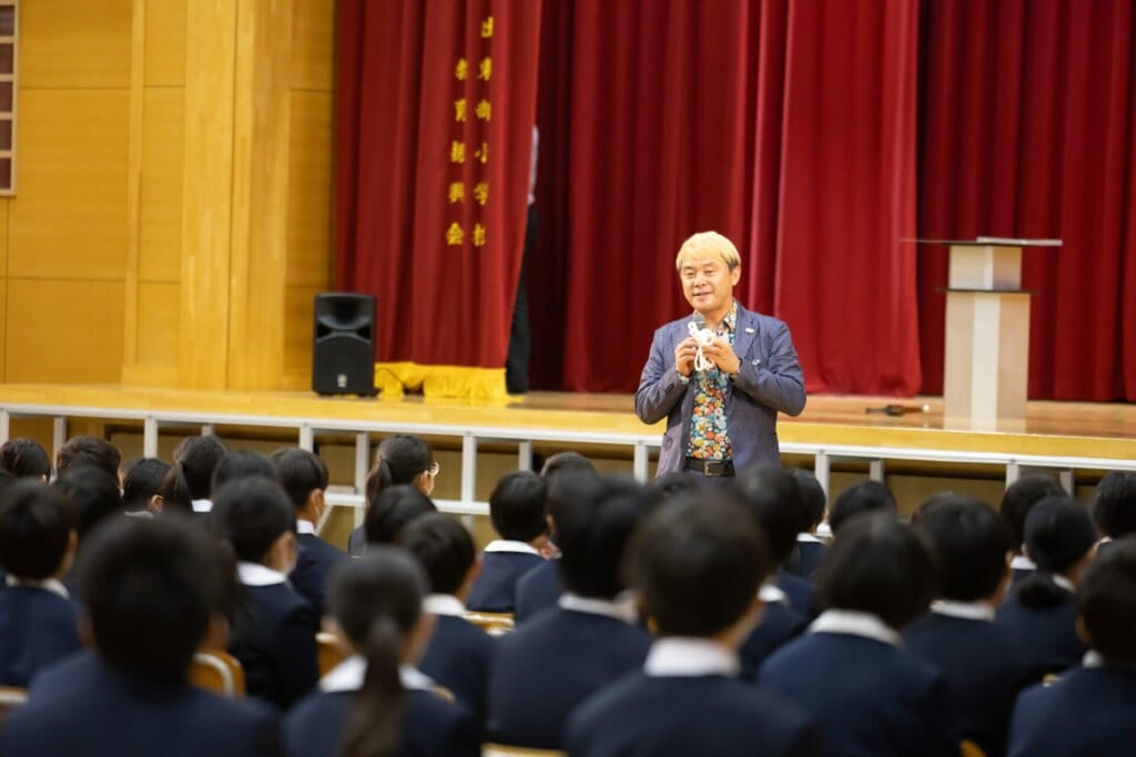 【PTA講演会 人気講師の選び方】「面白かった!」と言われる小学校・PTA講演会の3つの条件【2026年版】 5 戸出東部小学校60周年記念式典でマイクを持って子供たちとコミュニケーションを取りながら進めるトーキングマジック
