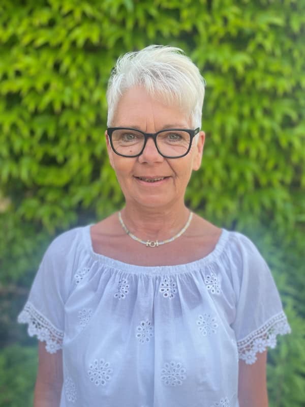 Porträtfoto von Birgit Kania, Begleitung von Beisetzungen beim Ruhewald Sandfort, vor einer grünen, mit Efeu bewachsenen Wand.