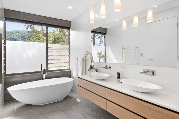 modern bathroom design in white and timber contrasting basin cabinet and white island bath tub