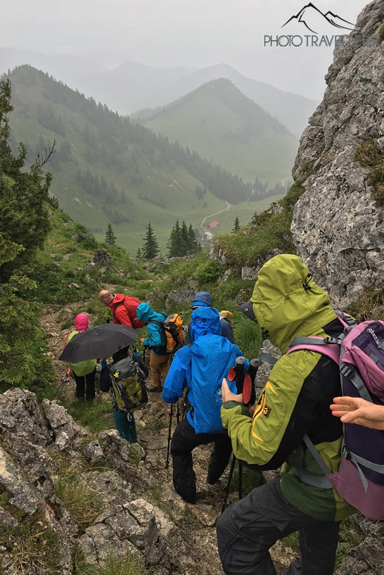 Die Teilnehmer der Wanderleiter-Ausbildung steigen im Regen einen felsigen Steig ab
