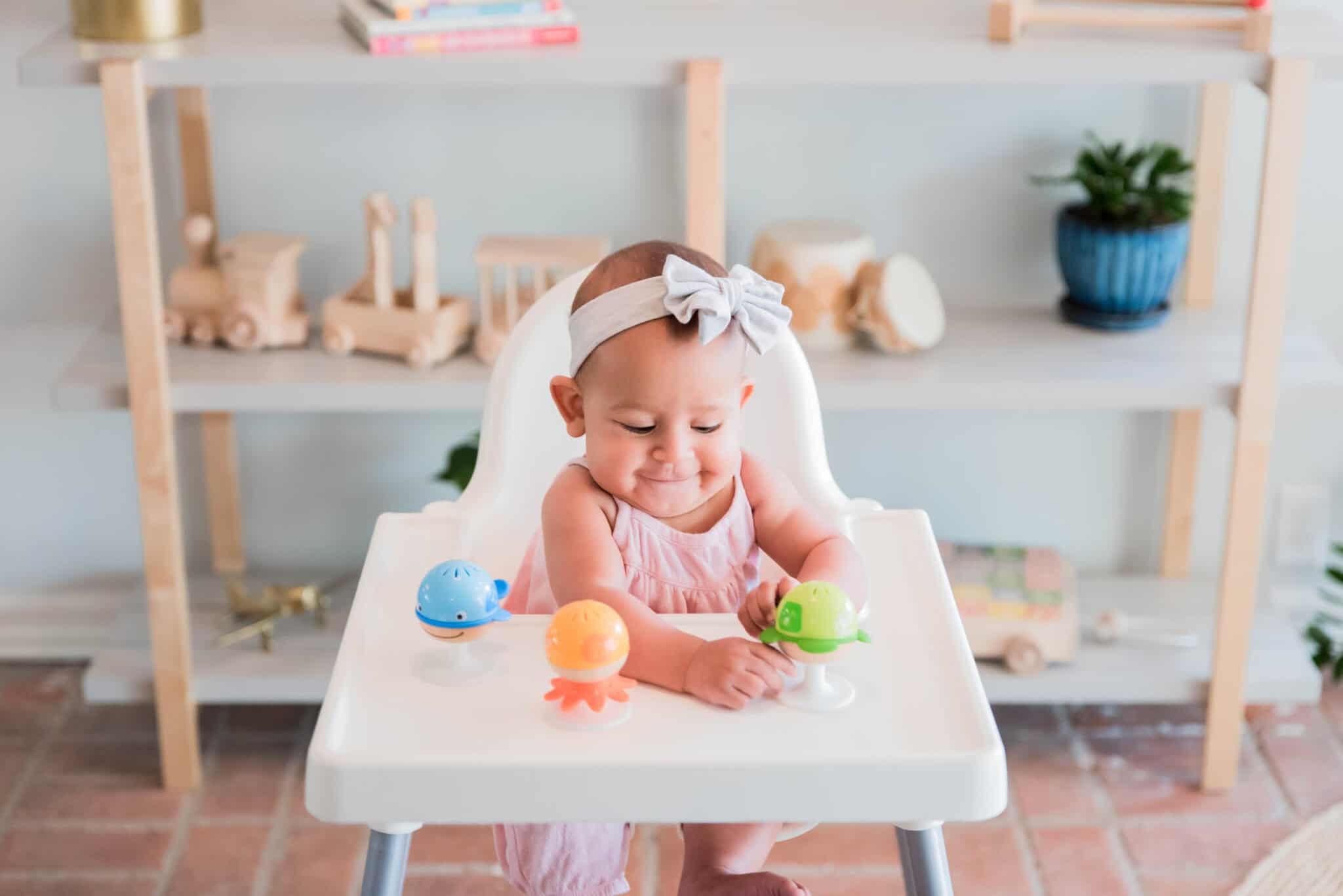 Baby playing with toys in high chair.