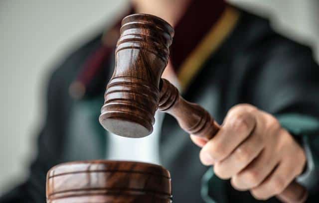 judge's hands with gavel in insurance payout lawsuit case