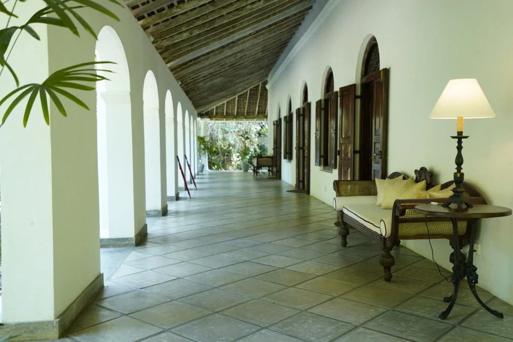 Corridor in Adigar's manor featuring a couch and lamp, with a view towards the Peacock Royal room.