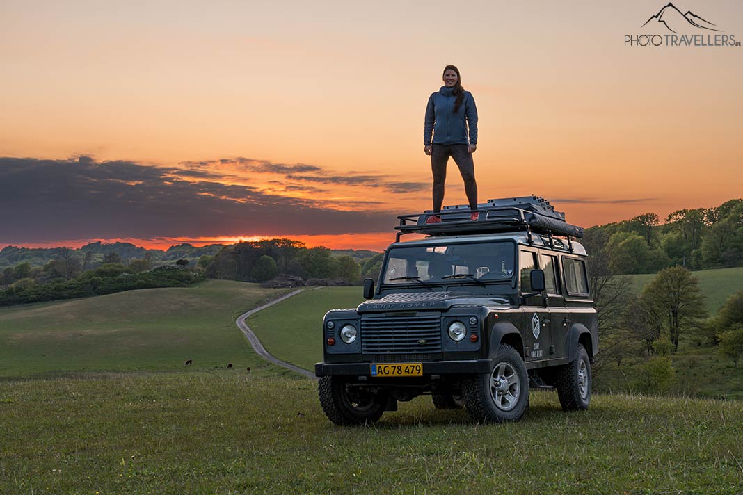 Reisebloggerin Biggi Bauer auf dem Dach eines Land Rovers im Abendlicht
