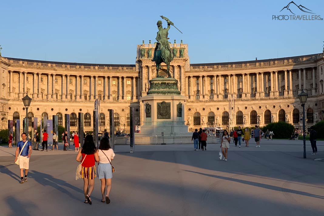 Spaziergänger vor der Wiener Hofburg im Abendlicht