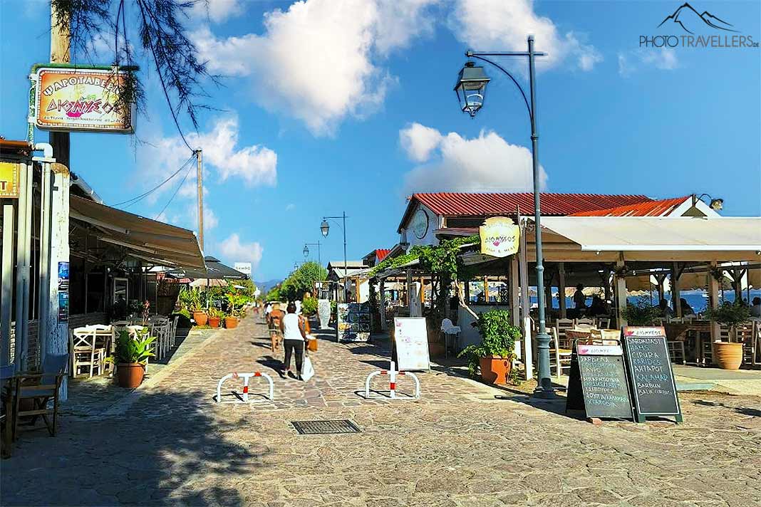 Menschen laufen vor den Tavernen an der Strandpromenade von Skala Kallonis