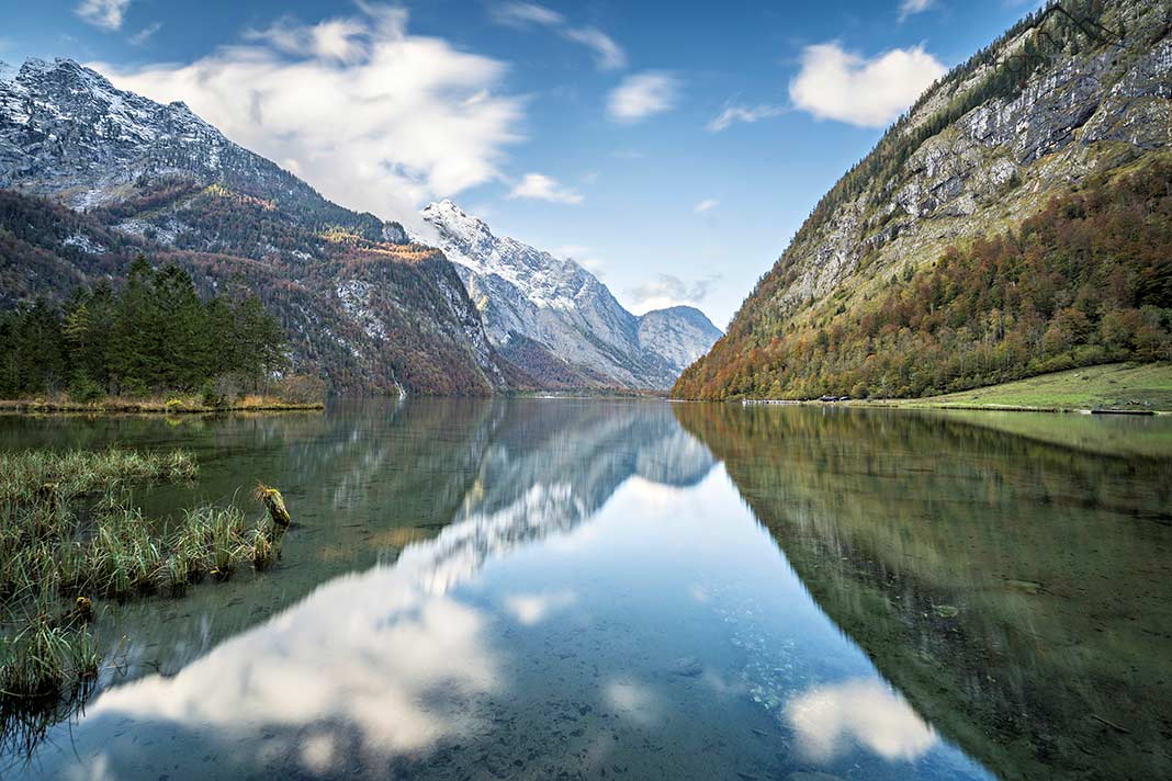 Der Blick vom Ufer über den Königssee, in dem sich die umliegenden Berge spiegeln