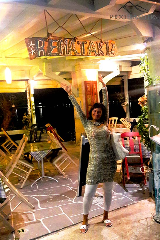 Eine Frau hebt die Arme und lächelt vor einer leeren Taverne