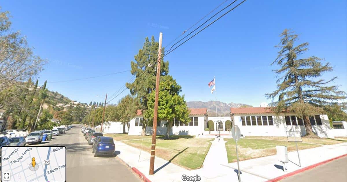 McKevett Elementary School in Santa Paula, CA, with white buildings and a red-tiled roof. The image shows a clear blue sky, the school's entrance, and a street with parked cars. This photo relates to the LA school abuse and child molestation arrest case.