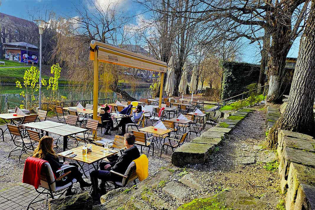 Mehrere Gäste sitzen auf einer Terrasse eines Restaurants am Fluß Bega in Timisoara