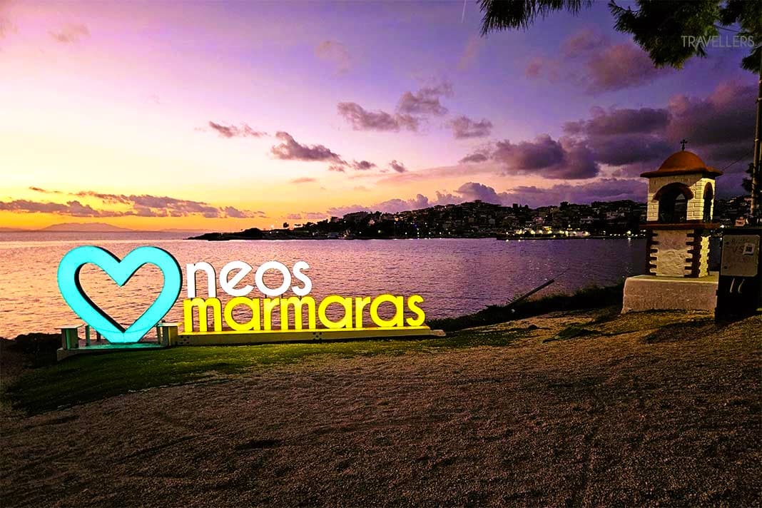 Ein Sonnenuntergang am Strand in Violett-Tönen mit einer Leuchtreklame von Neos Marmaras mit Herz