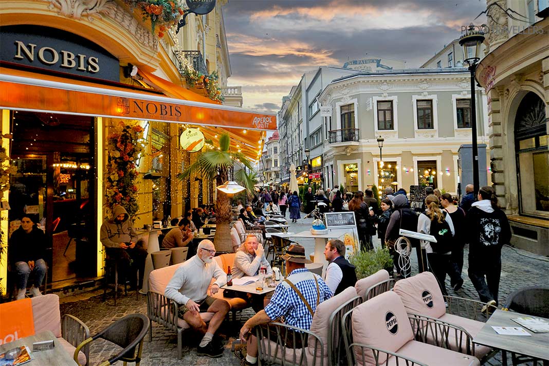 Menschen sitzen in der Fußgängerzone an den Tischen von Bars in Bukarest