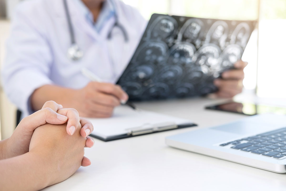 The neurosurgeon reviews and x-ray while conversing with a patient.