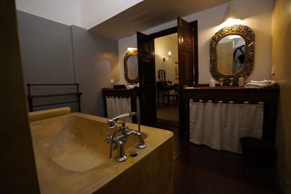 The Connelian Room's bathroom showcases a large tub and a stylish mirror, emphasizing luxury and comfort.