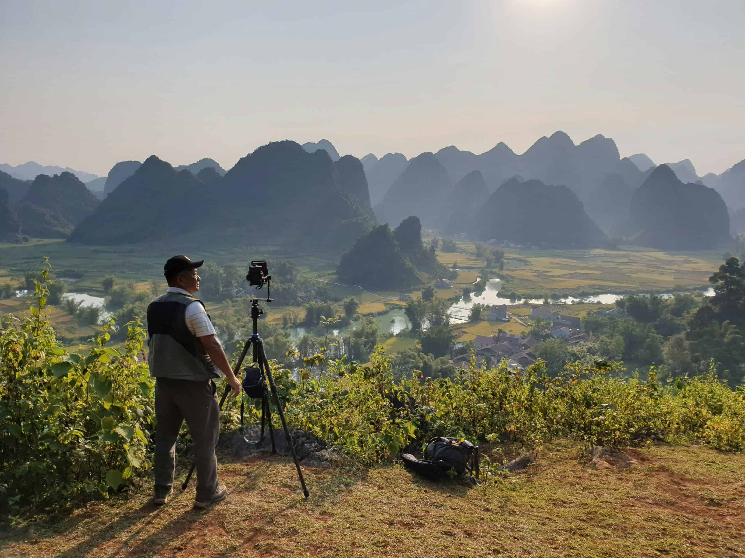 How to Shoot Panoramas with Canon EOS 6D / 6D Mark II & Sony FE 16-35mm f/2.8 GM 11 Man Standing Near Black Tripod Viewing Mountains for panorama planning
