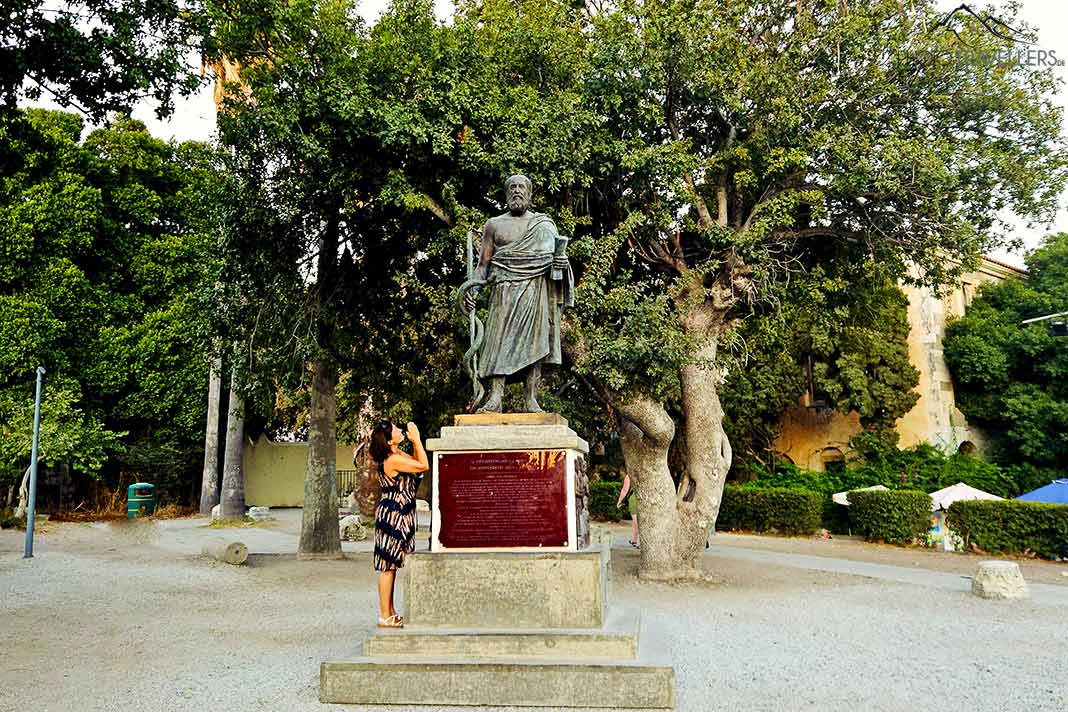 Eine Frau betet die Statue des Hippokrates an vor dem gleichnamigen Baum
