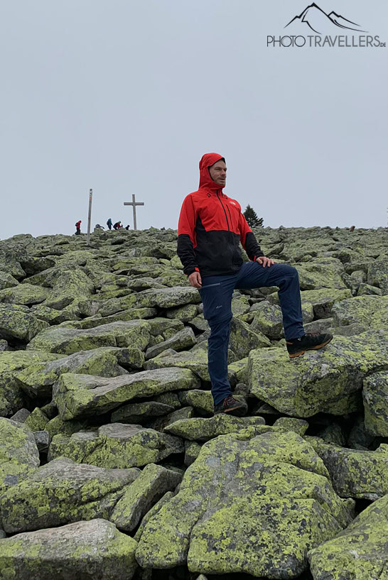 Reiseblogger Florian Westermann trägt eine rote Jacke und blickt auf dem Blockmeer am Lusen in die Ferne
