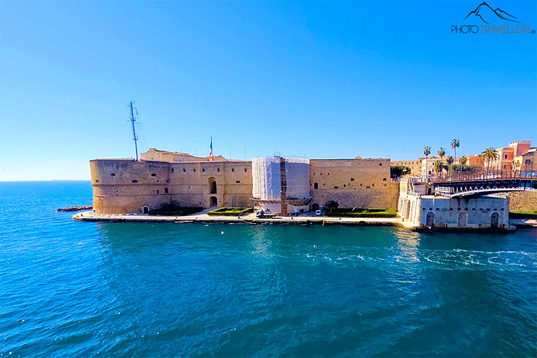 Die hellroten Mauern des Castello Aragonese ragen auf einer Landspitze in das Ionische Meer