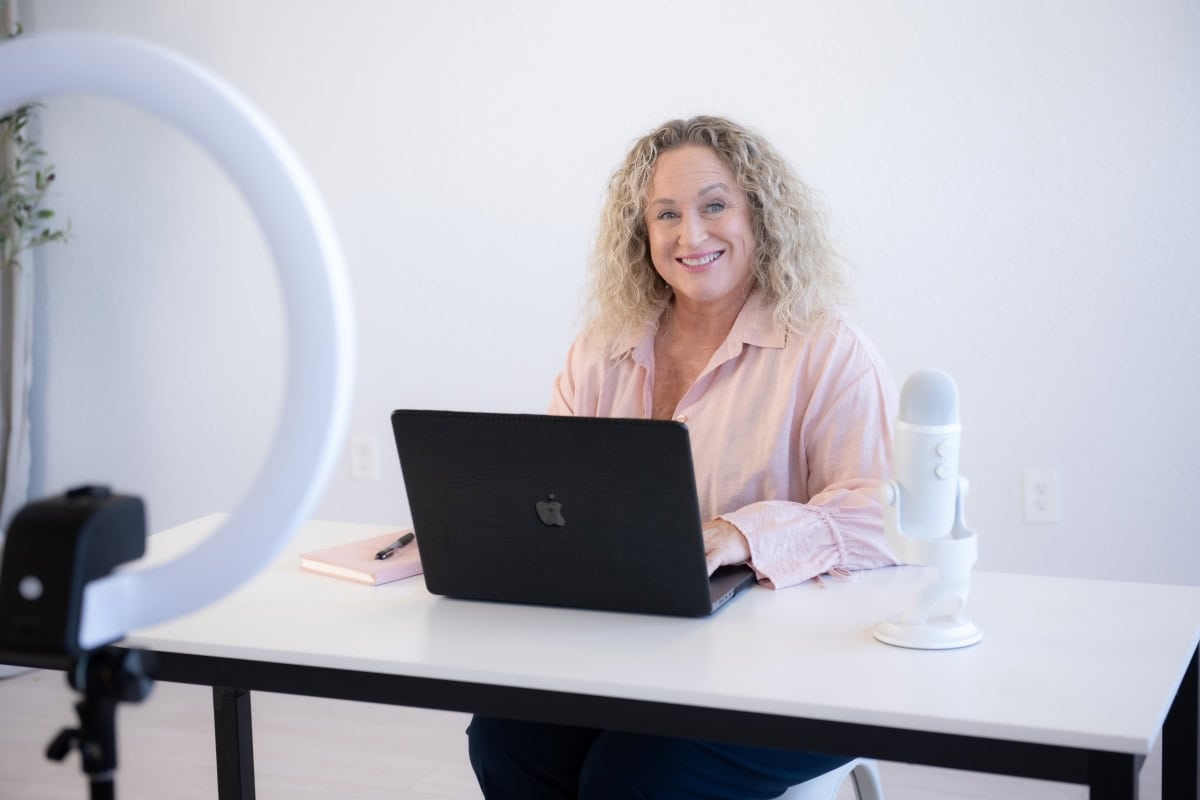 Woman smiling at laptop during video recording session about SOP creation and overcoming operational bottlenecks.