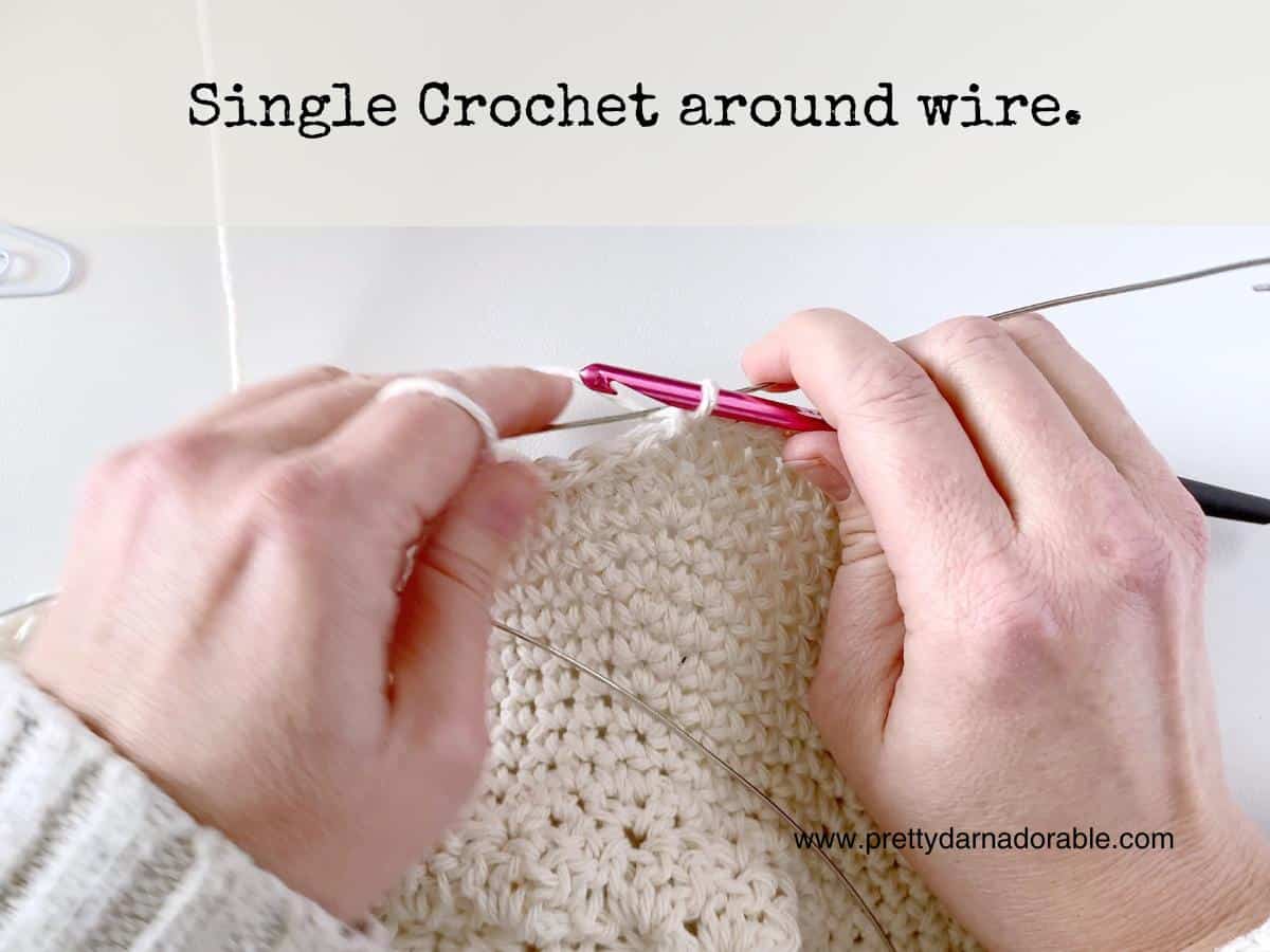 two hands crocheting around a wire