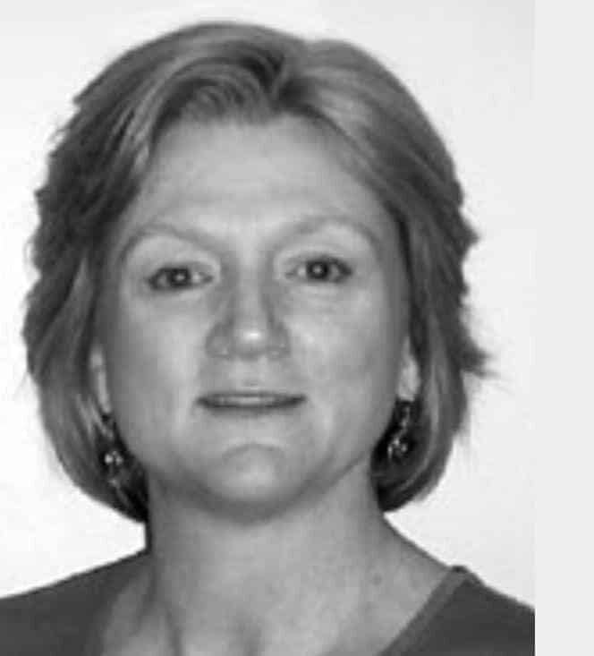 A woman with short blonde hair looks directly at the viewer, likely an educator, in a black and white photo.