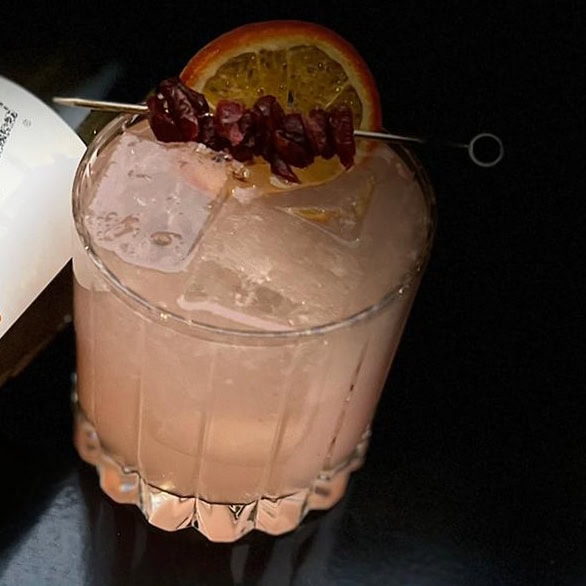 Cocktail with sweet wine, blood orange, and berries on the rim of the glass.