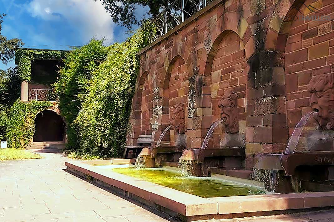 Drei Wasserspeier ragen aus der rotbraune Steinwand der St.-Germain-Terrasse