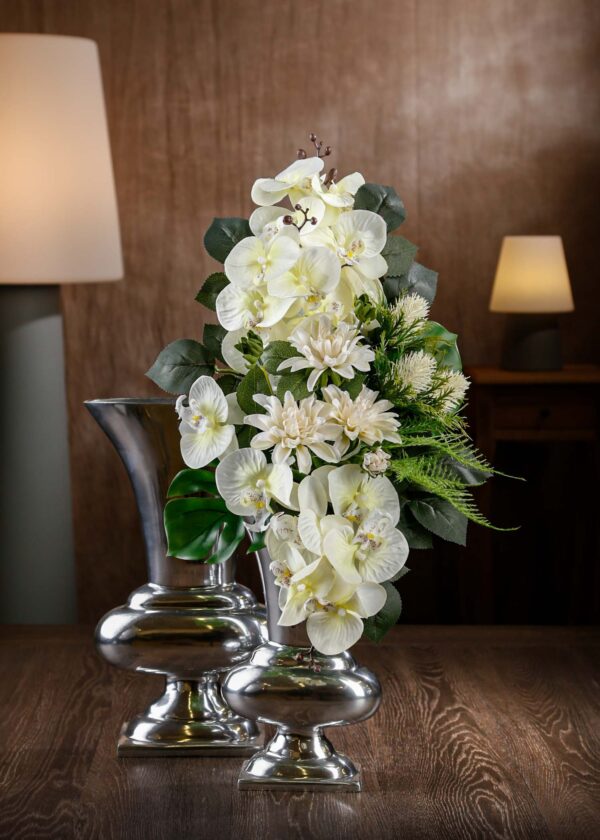 Vista frontale di un bouquet di fiori finti per cimitero, con orchidee bianche e fiori crema su sfondo verde – un tocco di eleganza e serenità senza manutenzione