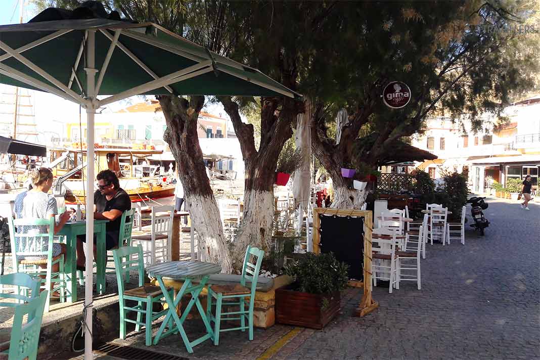 Tische und Stühle mit einigen Menschen am Hafen von Agia Marina