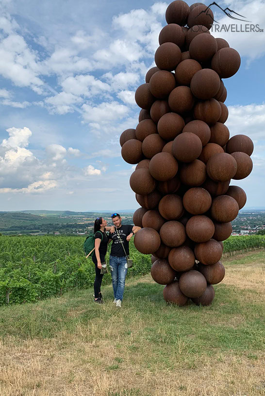 Die Reisejournalisten Biggi Bauer und Florian Westermann vor einer riesigen Trauben-Skulptur auf dem Weinweg Langenlois