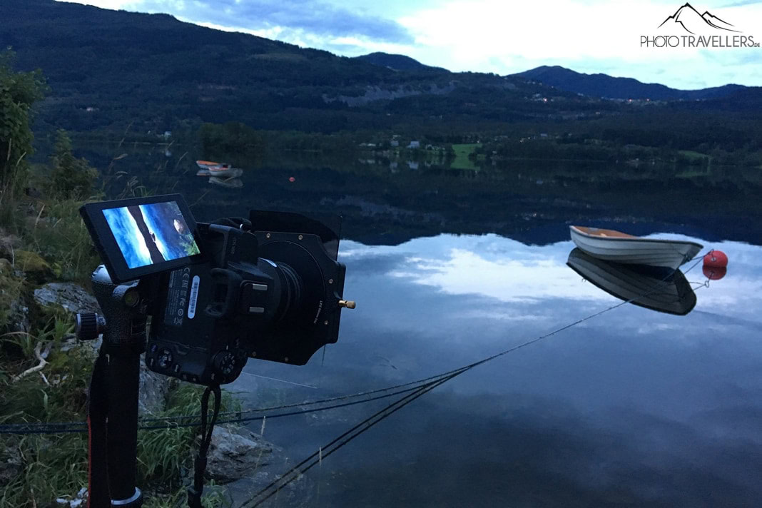 Die Canon EOS M50 mit ausgeklappten Dislpay im Dämmerlicht an einem See