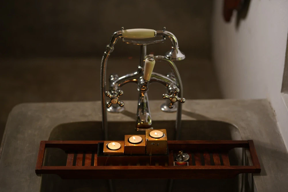 A vintage-style bathtub adorned with a candle holder and a decorative tap in the Peacock Royal room.