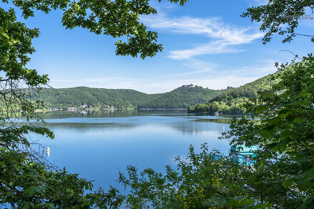 Blick durch Bäume auf den Edersee mit Schloss Waldeck