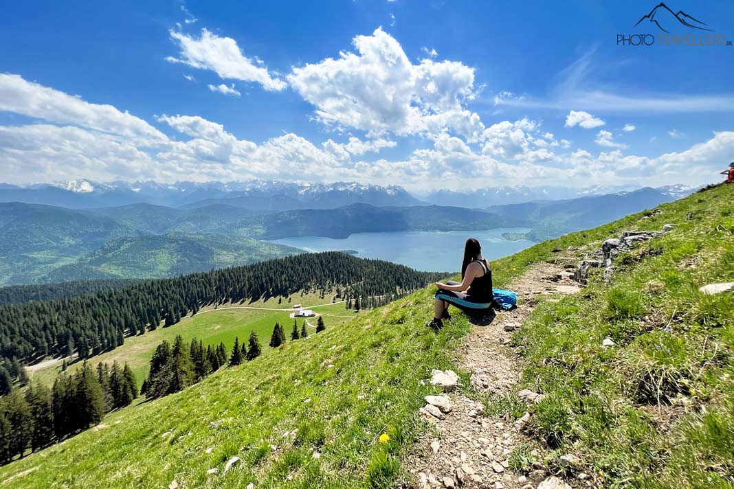 Reisebloggerin Biggi Bauer sitzt auf dem Jochberg und blickt auf den Walchensee