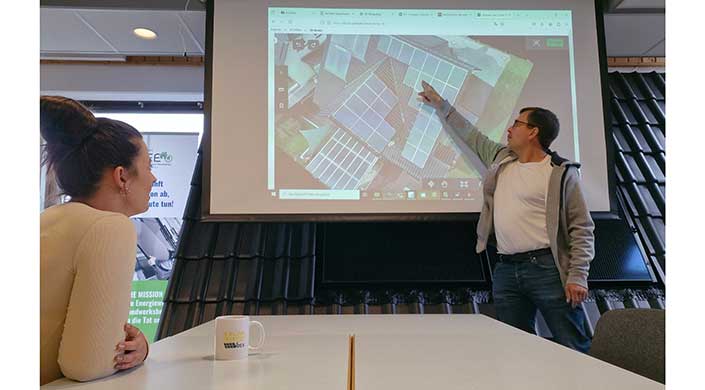 Projektor zeigt eine Desktopansicht mit Luftbild von Gebäuden, die Solarpaneele auf den Dächern installiert haben.