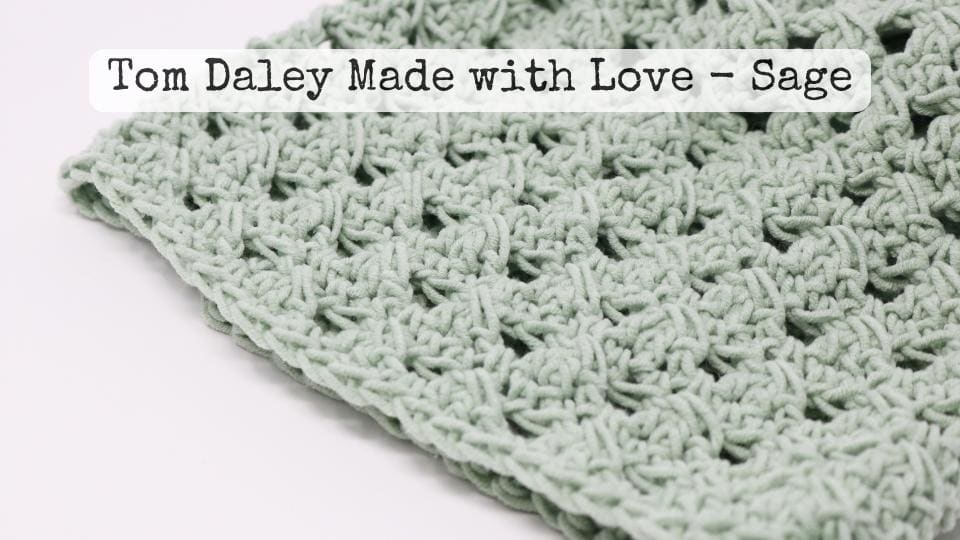 A close-up of a sage green crochet fabric with a textured, open pattern, perfect for crafting a simple granny stitch crochet beanie. Text overlay reads: Tom Daley Made with Love – Sage.