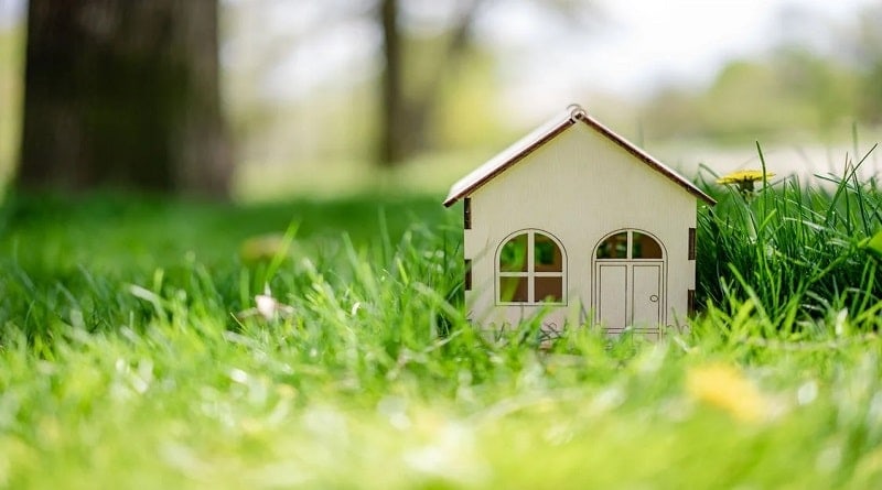 Downsizing Your Home / Tiny miniature replica of a home, sitting in the grass in the sunshine