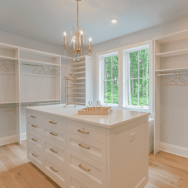 Custom walk-in closet with white shelving, center island, gold hardware and chandelier in a Florida home