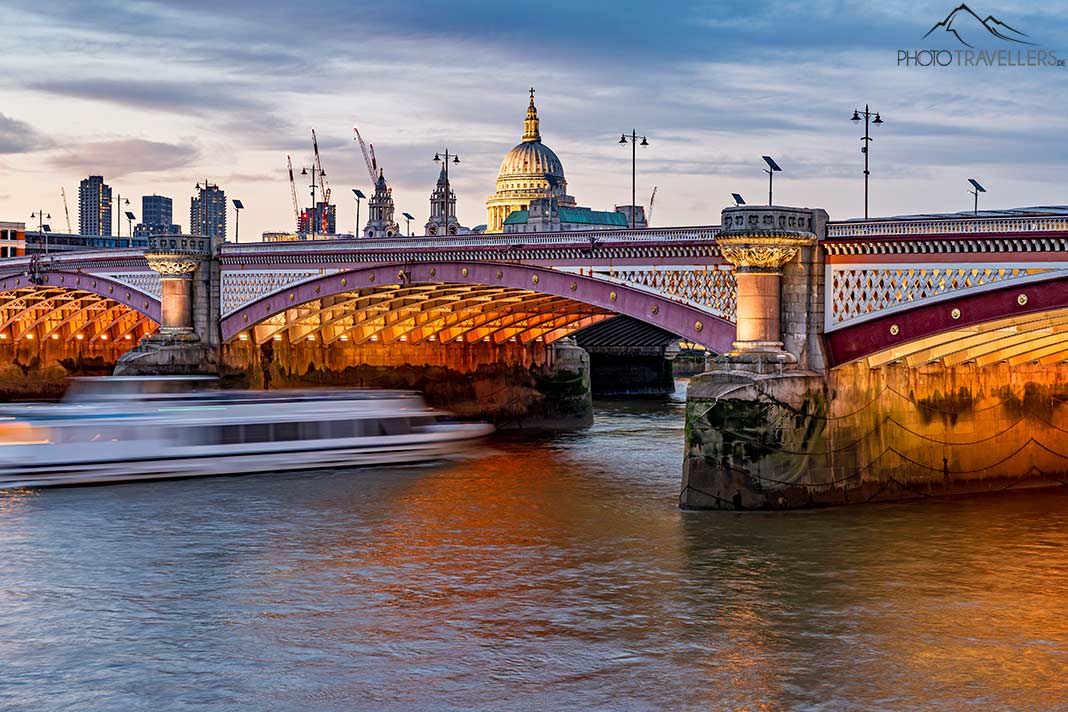 Ein Boot fährt durch die beleuchtete Blackfriars Bridge, London