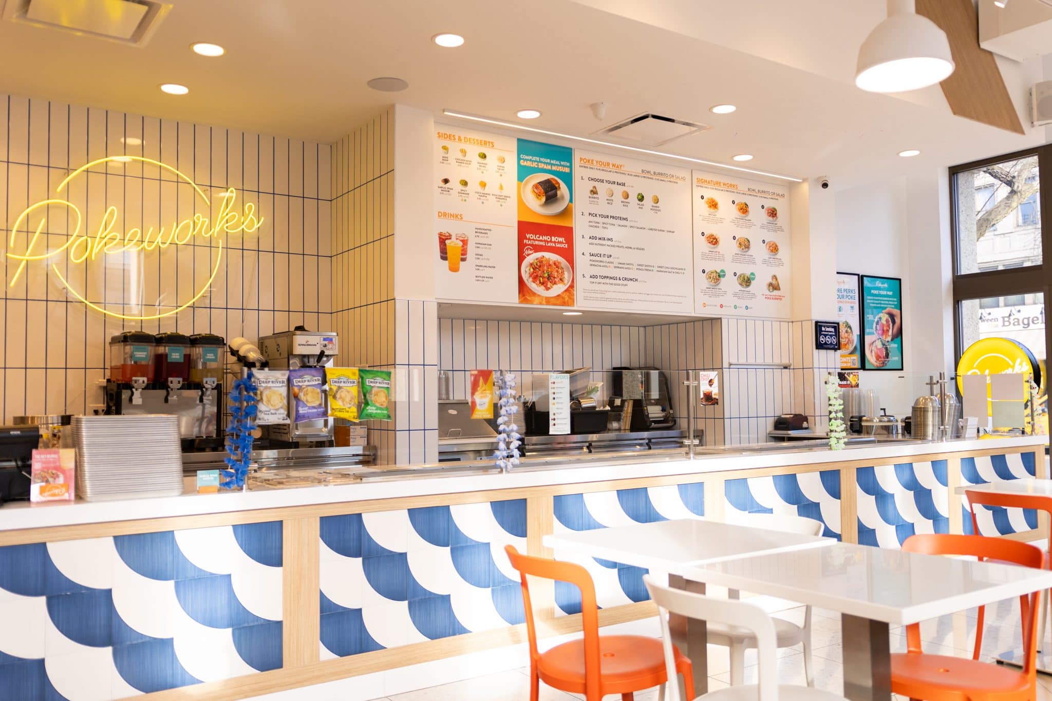 Pokeworks interior with blue tile counter, neon logo, and menu boards
