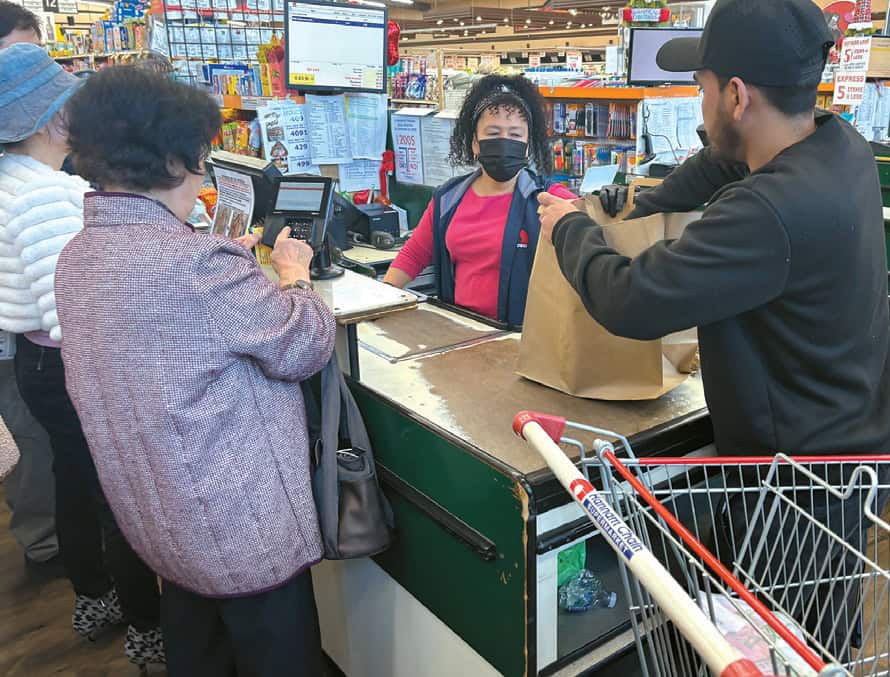 Customer packs groceries into a paid paper bag at a Hannam Chain checkout in LA after the plastic bag ban took effect