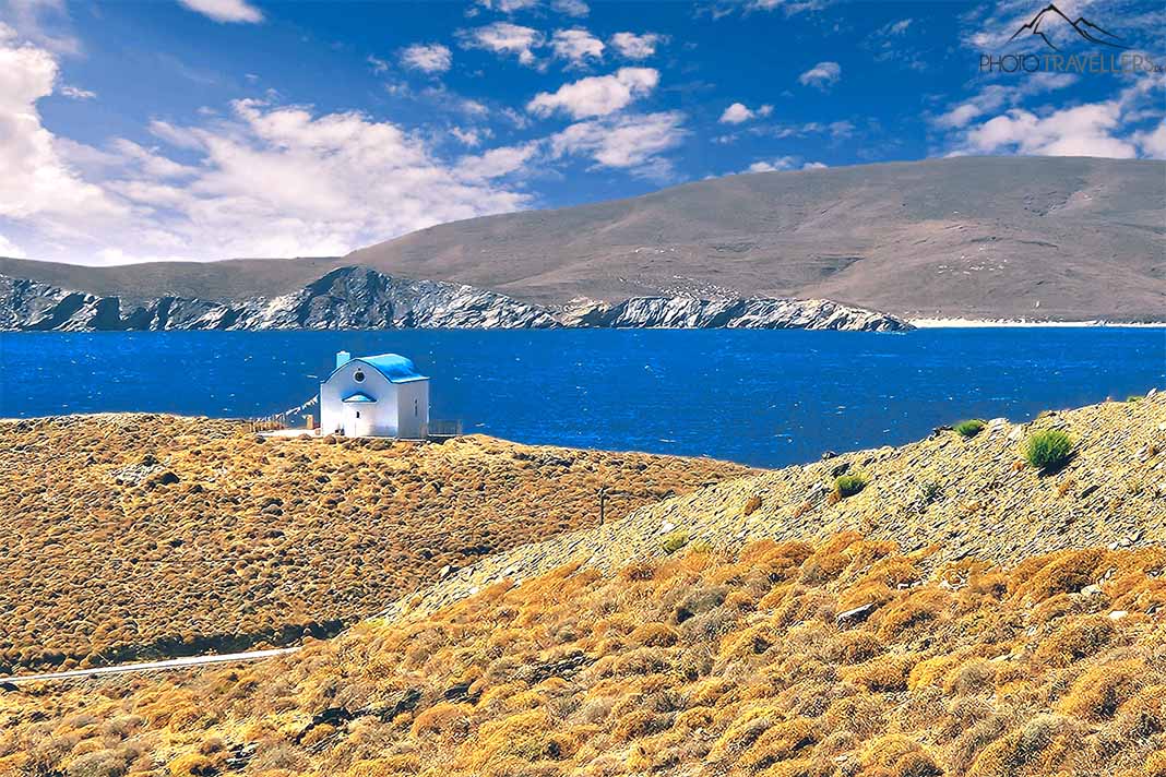 Kapelle mit blauem Dach am Meer dahinter unbewachsene Hügel