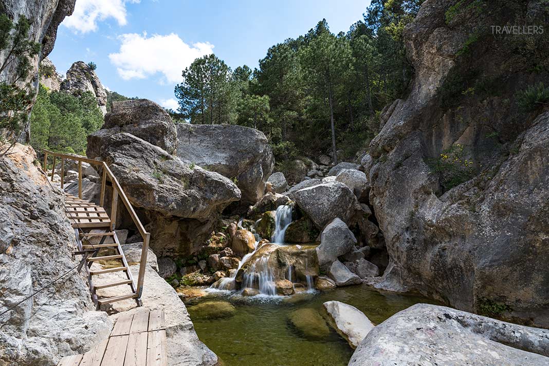 Ein kleiner Wasserfall, daneben ein Holzsteg