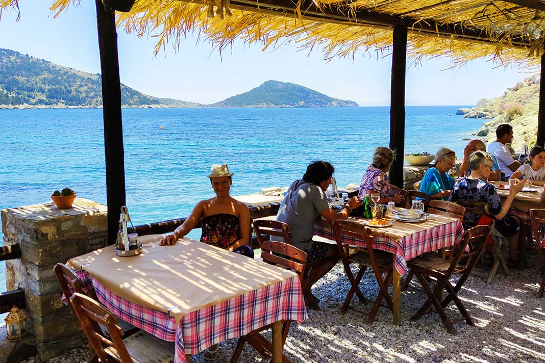 Gäste sitzen an den Tischen einer Taverne am Meer
